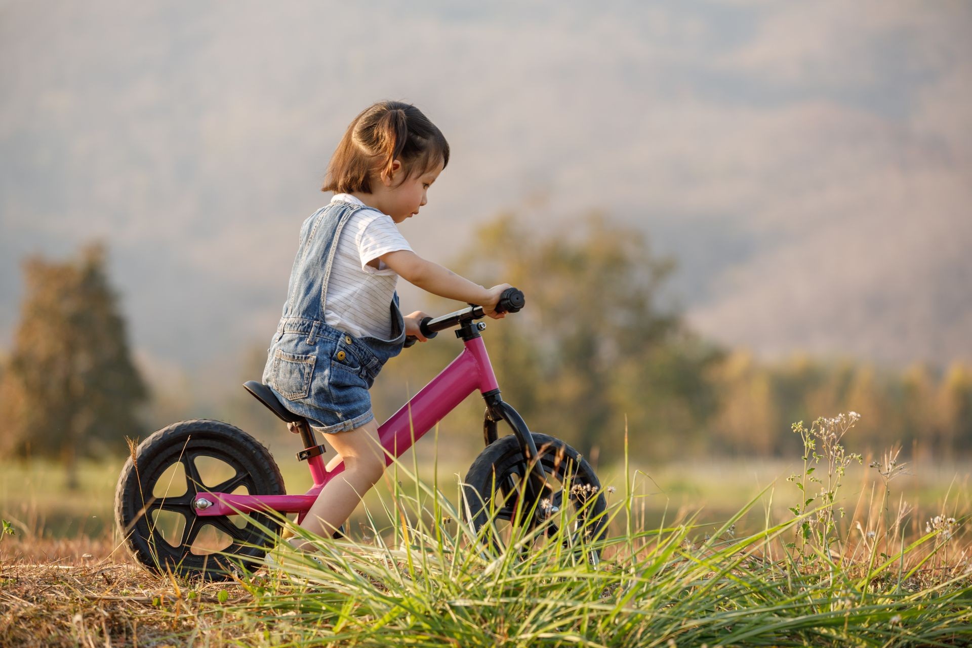 Happy child riding a pink bike in the park